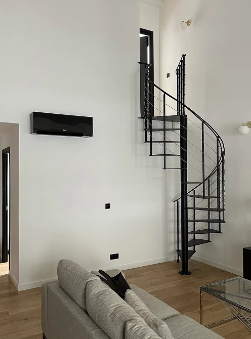 Climatiseur mural noir dans un salon moderne avec escalier en colimaçon