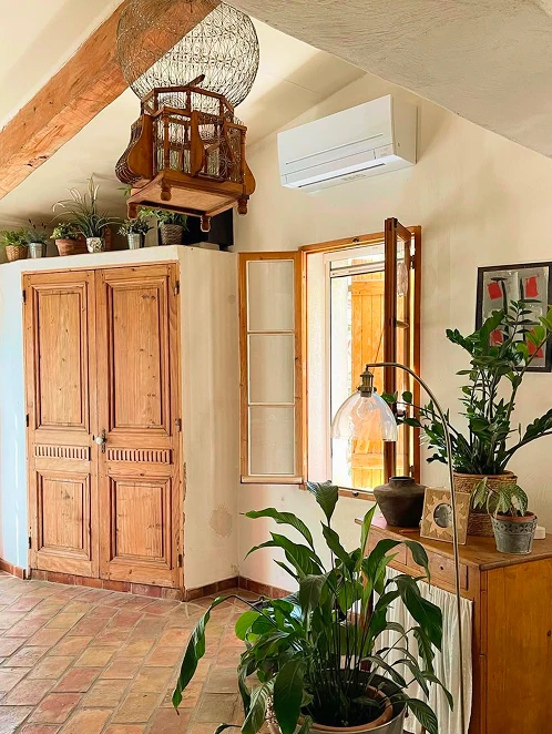 Climatiseur mural blanc dans une maison de campagne avec poutres apparentes