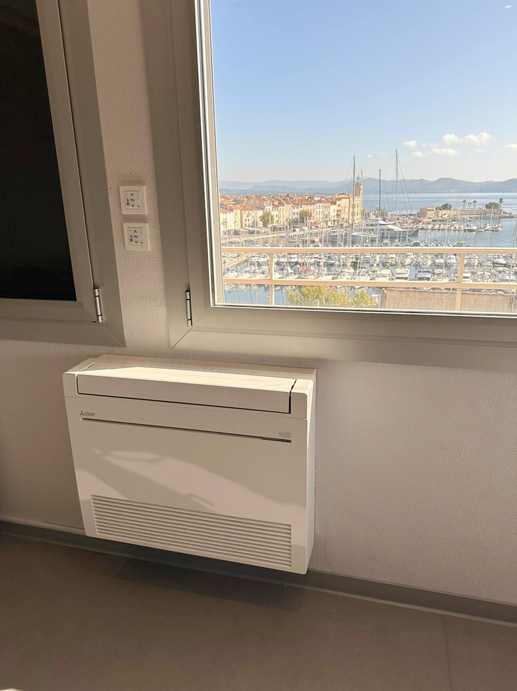 Climatiseur mural sous une fenêtre avec vue sur la mer